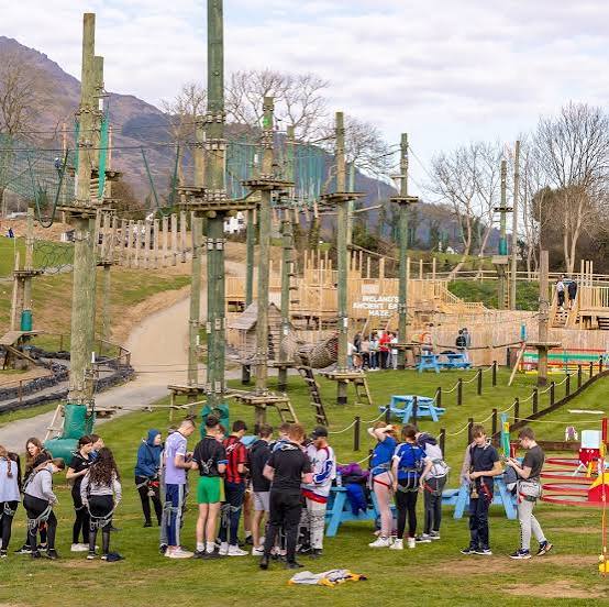 The Skypark site under the Cooley Mountains, with high ropes
                                          towers and a group gearing up below.