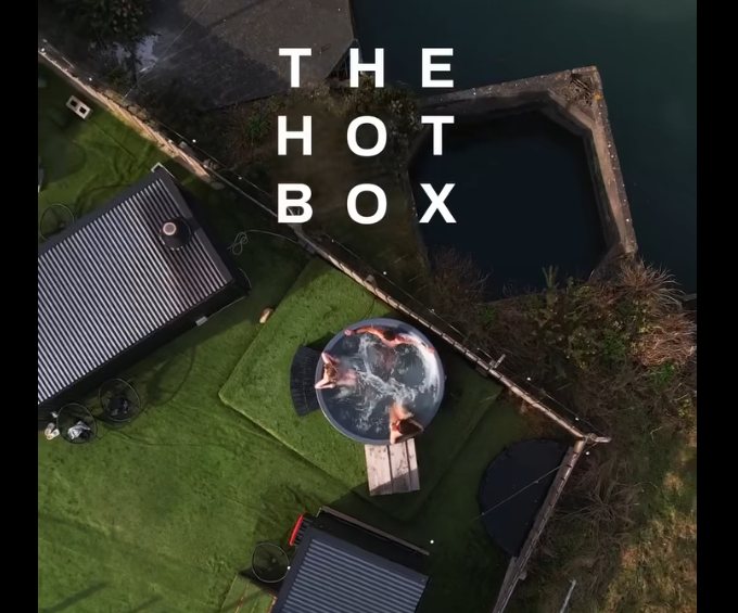 The Hot Box Sauna from above: sauna cabins on the grass beside
                    Carlingford Lough, with a cold plunge tub between them.