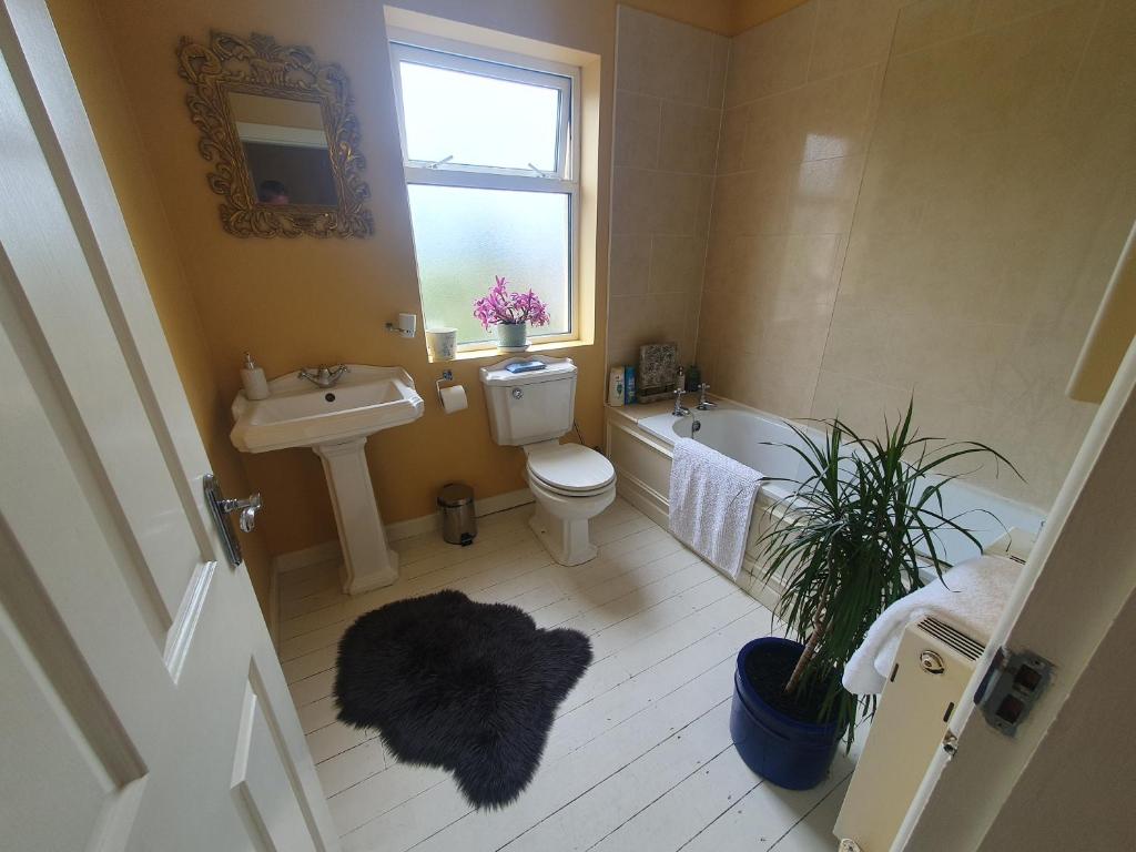 A bathroom with a full-size bath, pedestal basin and WC, painted in ochre
                      with a frosted window.