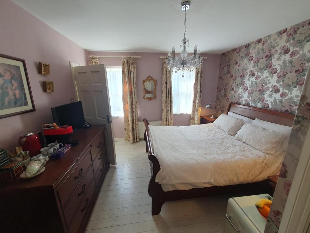 Bedroom one: a sleigh bed made up in white against floral wallpaper, with a
                    chandelier, a dressing table and windows onto Dundalk Street.