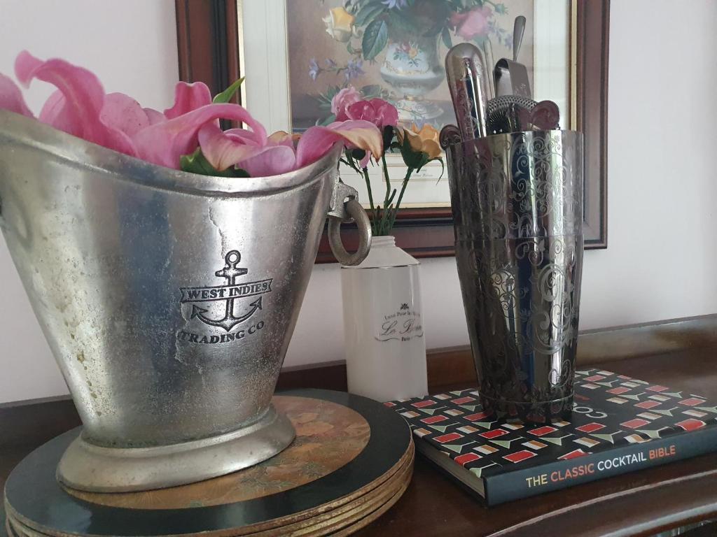 Ice bucket, cocktail shaker and bar tools beside a cocktail book.