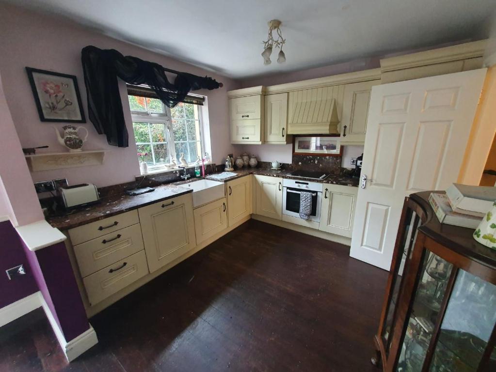 The kitchen at The Retreat: cream units, marble worktops, a butler sink under
                  the window and a built-in oven and hob.
